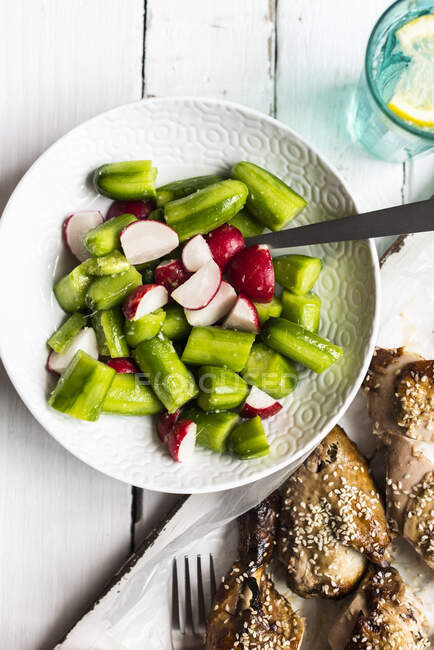 Baked cucumber salad with radishes and sesame chicken — Stock Photo