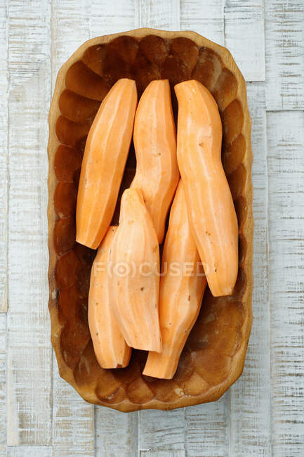 Batatas doces descascadas em um prato de madeira — Fotografia de Stock