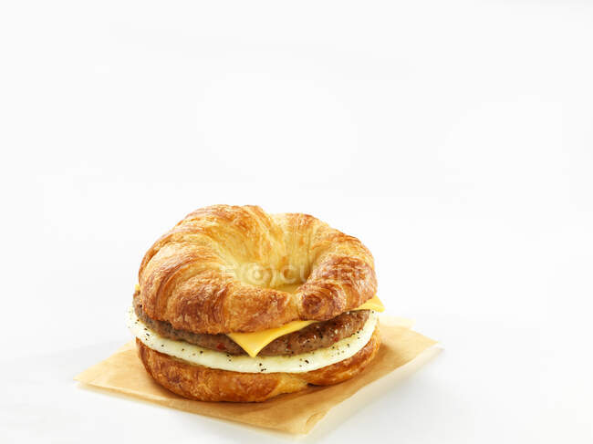 A croissant burger with cheese and egg against a white background — Stock Photo
