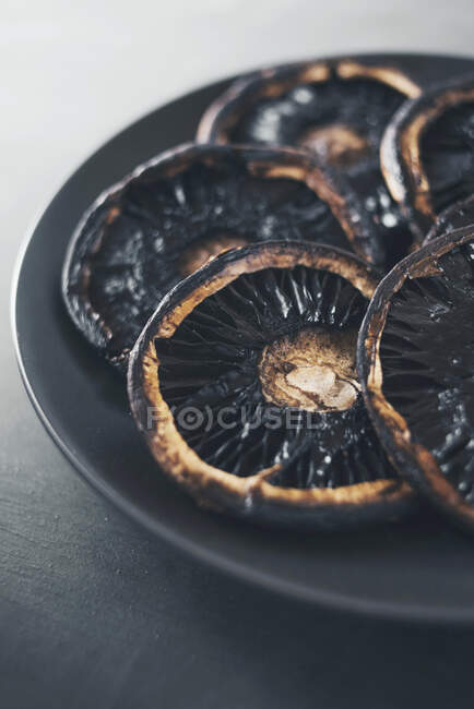 Fried portobello mushrooms on a black plate — Stock Photo