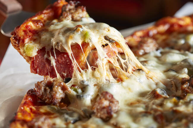 Пицца с колбасой и сыром, нарезанный — стоковое фото