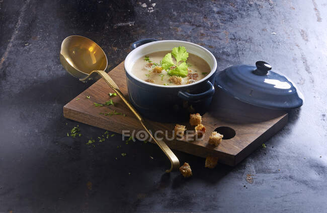 Potato soup with croutons in a ceramic pot on a wooden board — Stock Photo