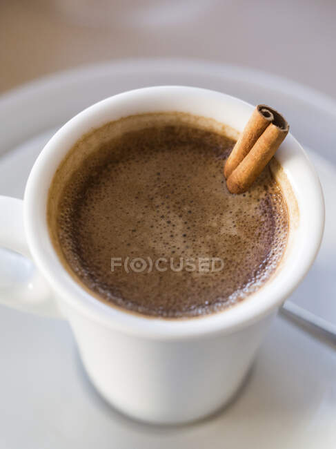 Caffè portoghese servito in una tazza con un bastoncino di cannella (primo piano) — Foto stock