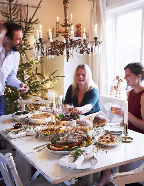 Uma família sentada ao redor de uma mesa para o jantar de Natal — Fotografia de Stock