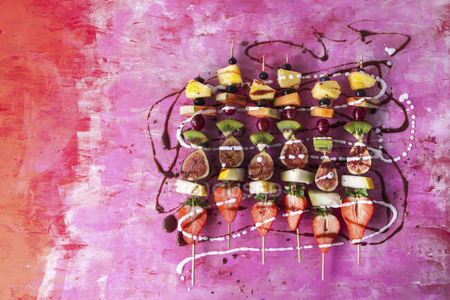 Fruit kebabs with chocolate sauce and coconut cream — Stock Photo