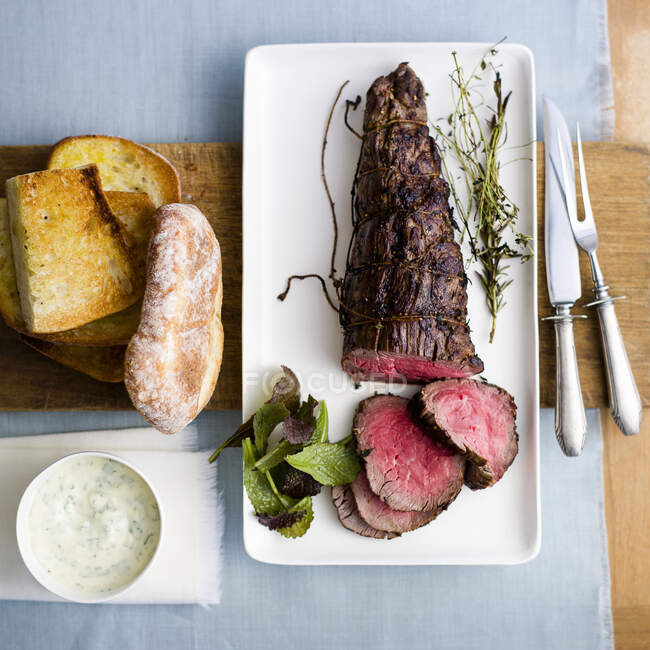 Rare roasted beef fillet with bread and sauce — Stock Photo