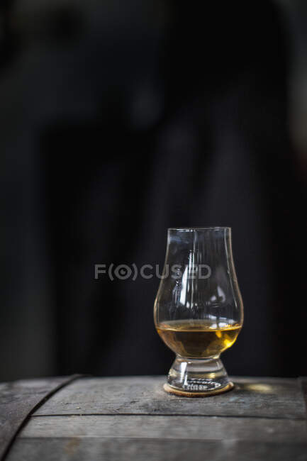 A glass of whisky on a wooden barrel — Stock Photo
