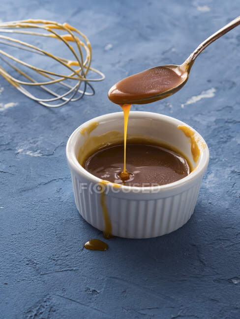 Home made salted caramel in a bowl over blue background — Stock Photo