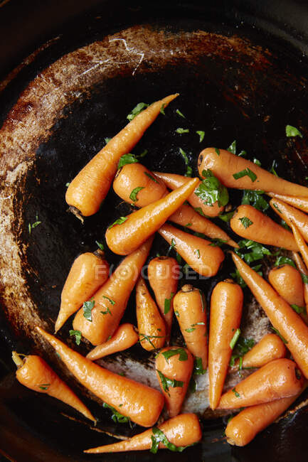 Сира морква в кошику з зеленим листям в саду на чорному тлі — стокове фото
