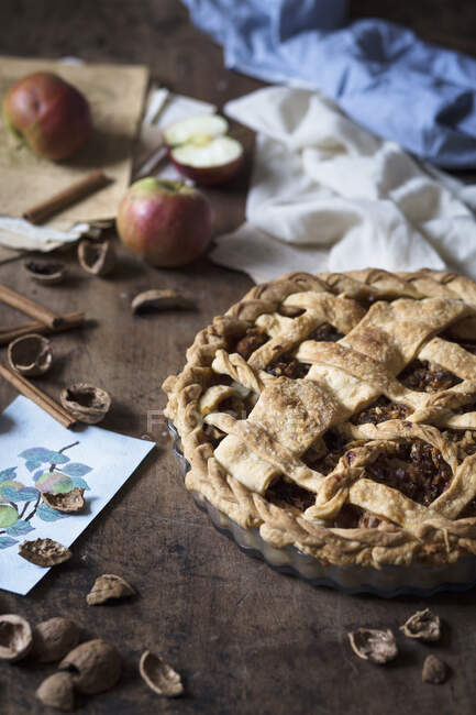Rustic apple pie with walnuts, cinnamon sticks and apples, close up shot — Stock Photo