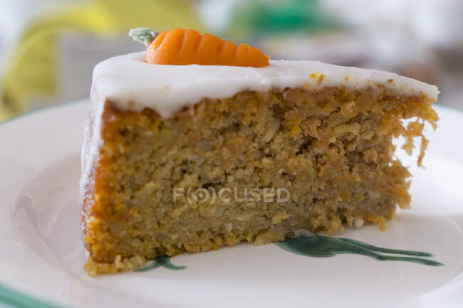 A slice of carrot cake with icing and marzipan carrots — Stock Photo