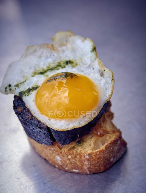 Canapes with blood sausage slice and quail egg — Stock Photo