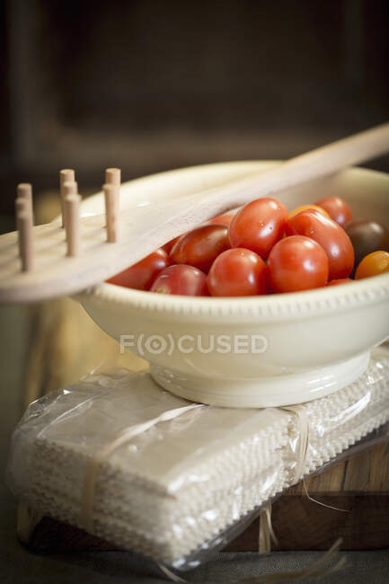 An arrangement of cherry tomatoes, a pasta fork and a pack of pasta — Stock Photo