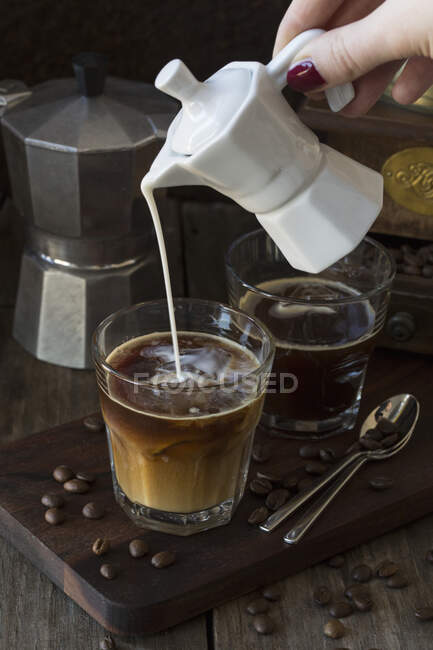 Leite sendo derramado em um copo de café — Fotografia de Stock