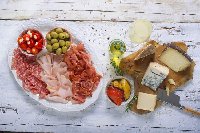Plateau de fromages et saucisses aux olives, légumes farcis et vin blanc — Photo de stock
