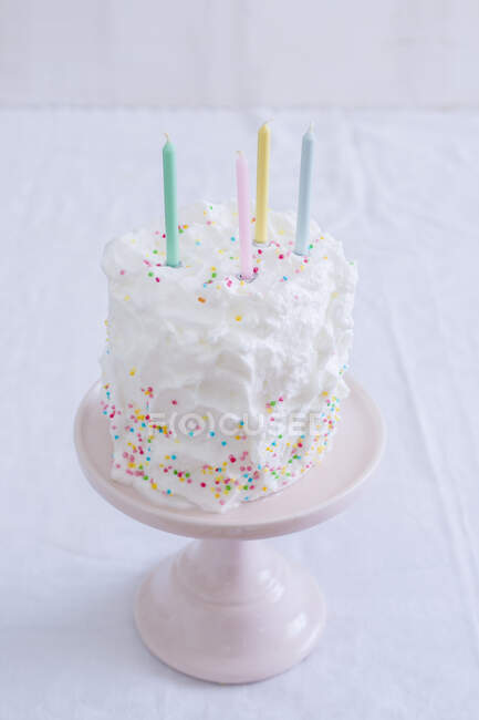 Cake with sprinkles decoration on a pink stand — Stock Photo