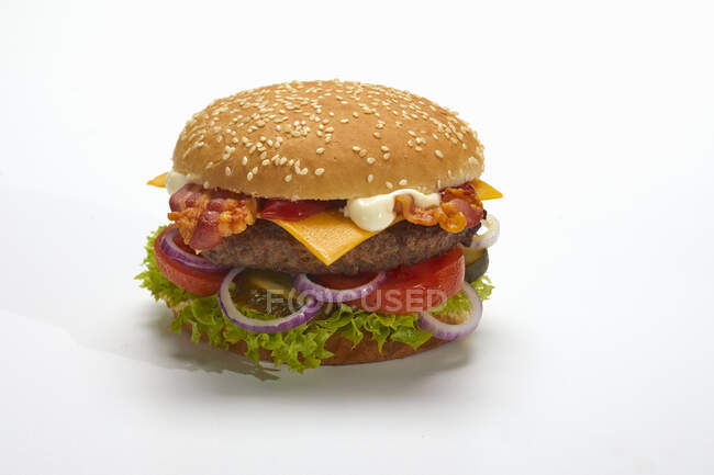 A hamburger with bacon and cheese against a white surface — Stock Photo