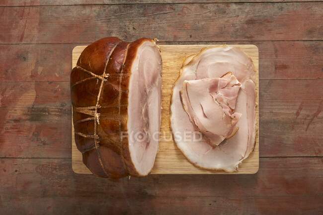 Roast ham, sliced, on a wooden board — Stock Photo
