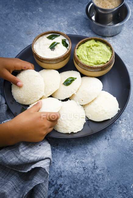 Traditional breakfast with Idli (rice cakes), coriander chutney, coconut chutney and coffee (South India) — Stock Photo