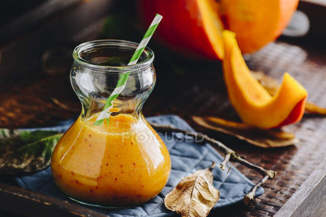 Pumpkin smoothie in a carafe with a straw — Stock Photo