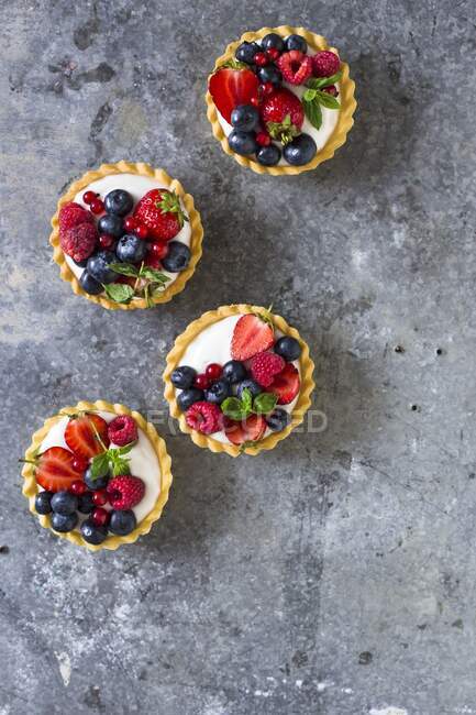 Mixed berry tarts with vanilla cream — Stock Photo