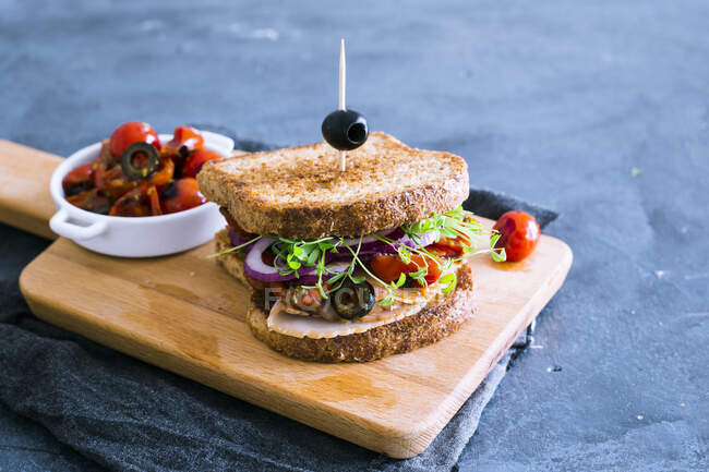 Сэндвич с индейкой с песто, ростками, оливками, помидорами черри и луком — стоковое фото