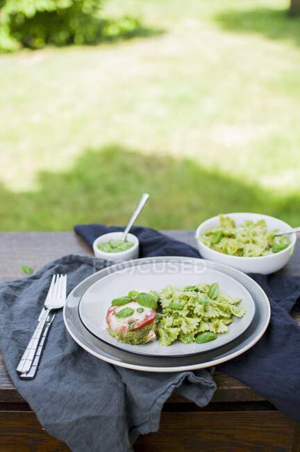 Baked chicken breast with pesto noodles on table in garden — Stock Photo