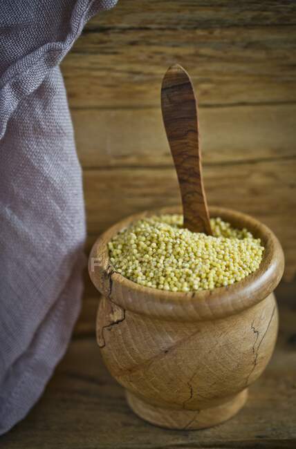 Dry Millet in wooden bowl with wooden spoon — Stock Photo