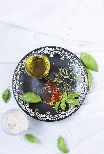 Sal, aceite de oliva, copos de chile y albahaca - foto de stock