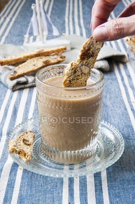 Biscotti with figs and nuts being dipped into coffee — Stock Photo