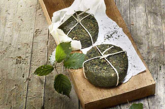 Two pecorino cheeses with stinging nettle rind on a wooden board — Stock Photo