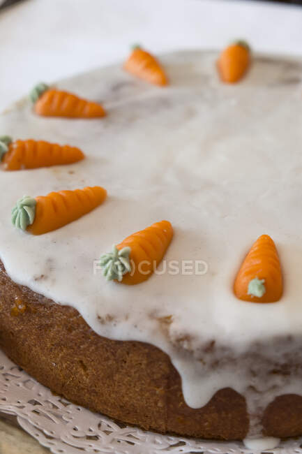 Carrot cake decorated with icing and marzipan carrots — Stock Photo
