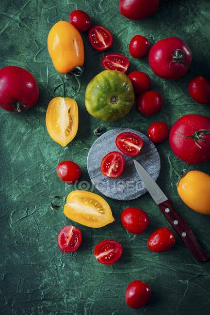 Diversos tomates, enteros y cortados a la mitad - foto de stock