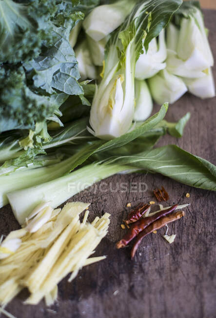 Una naturaleza muerta de ingredientes asiáticos con pak choi, col rizada, jengibre y chile - foto de stock
