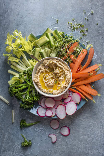 Homemade houmous with olive oil and pinenuts and raw vegetable for dipping — Stock Photo