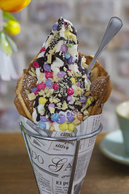 A bubble waffle with cream, Smarties, white chocolate and chocolate sauce — Stock Photo