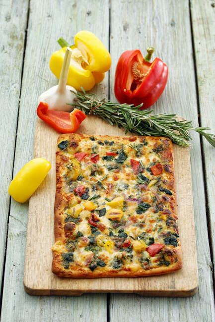 A pizza topped with peppers, garlic and rosemary — Foto stock