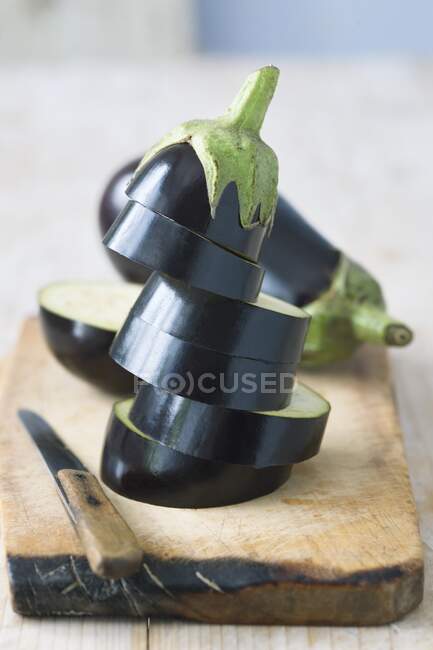 Whole and sliced eggplant on wooden chopping board — Stock Photo