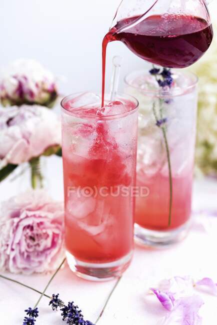 Gin tonic with blackberry syrup dripping from jug — Stock Photo