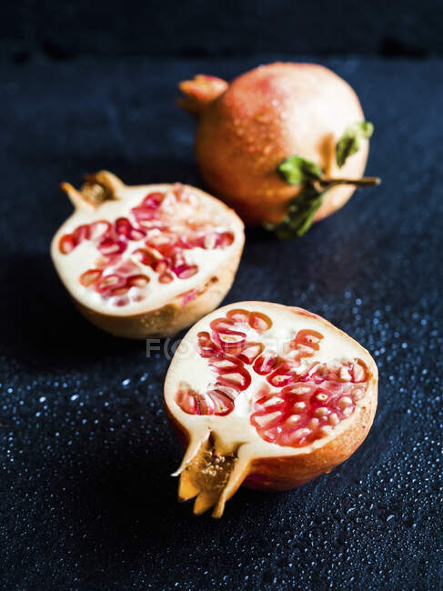 Fresh sliced organic pomegranate on a dark background — Stock Photo