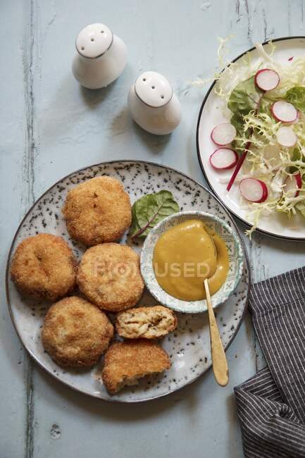 Fishcakes served with sauce and salad — Stock Photo