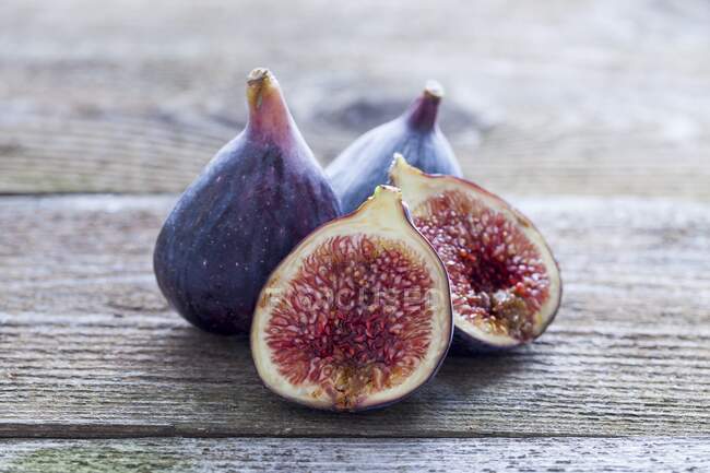 Fresh figs, whole and halved, on wooden table — Stock Photo