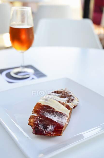 Iberian ham Pass on a white plate with a glass of Amontillado sherry — Stock Photo