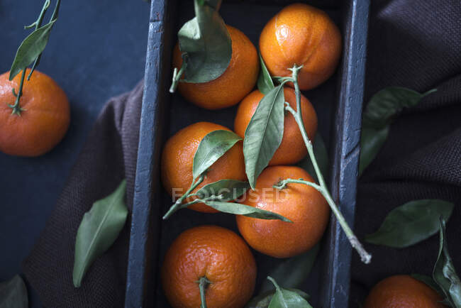 Fresh mandarins with leaves in crate, top view — Stock Photo