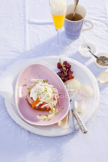 Huevos Benedicto con perejil, uvas y pétalos de flores - foto de stock