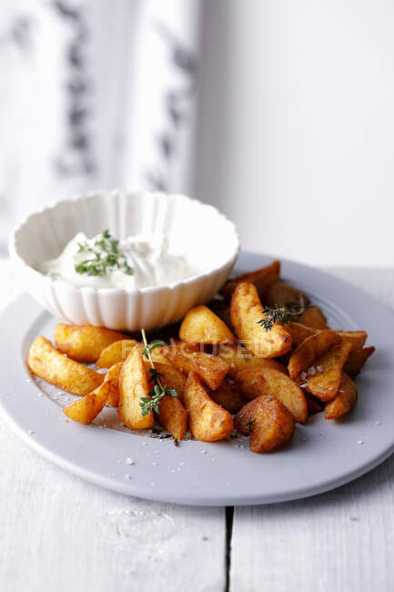Potato wedges with thyme and dip — Stock Photo