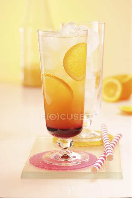 Bebida Orange Sunrise com cubos de gelo e fatias de laranja — Fotografia de Stock