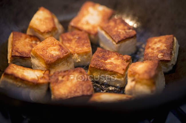 Cubos de tofu frito en un wok (de cerca) - foto de stock