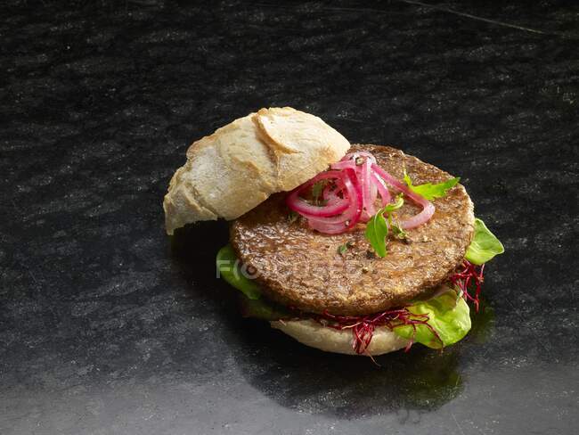 Primer plano de deliciosa hamburguesa con cebolla roja y lechuga - foto de stock