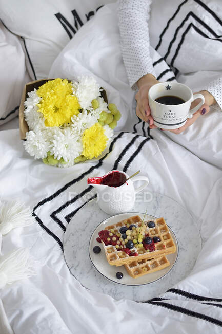Desayuno en la cama con café y gofres con bayas frescas - foto de stock